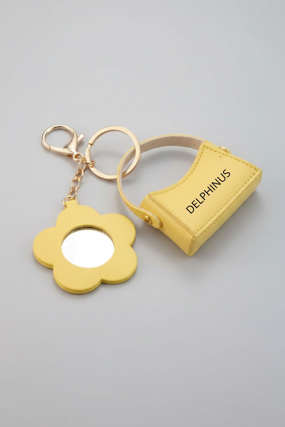 LE MIMOSA – Bijou de sac porte-clé jaune, fleur miroir et mini sac en cuir, quincaillerie dorée, fond gris studio, DELPHINUS