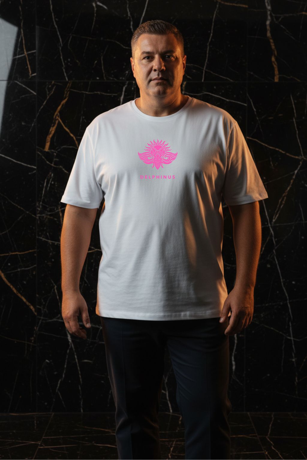 LA PÉTILLANTE CURVE – T-shirt unisexe blanc logo rose DELPHINUS, homme curve élégant, ambiance premium marbre noir et or, pantalon chino sombre, DELPHINUS