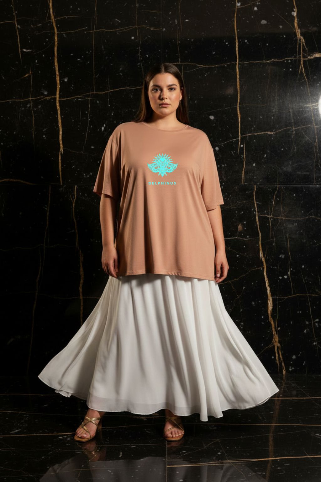 L'ÉVASION CURVE – T-shirt unisexe nude beige logo turquoise DELPHINUS, jeune femme curve naturelle, ambiance premium marbre noir et or, jupe blanche fluide et sandales dorées, DELPHINUS