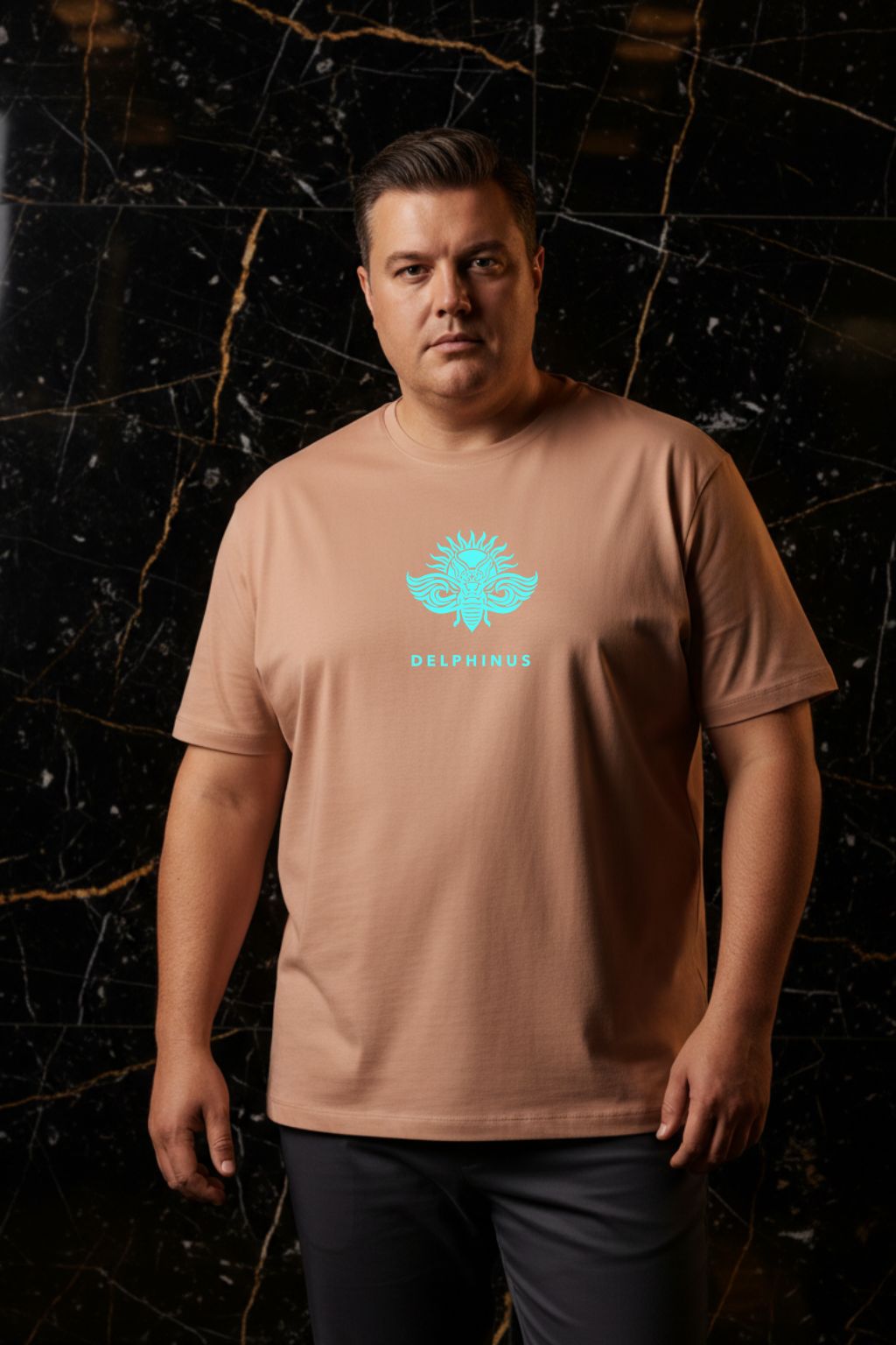 L'ÉVASION CURVE – T-shirt unisexe nude beige logo turquoise DELPHINUS, homme curve élégant, ambiance premium marbre noir et or, pantalon chino sombre, DELPHINUS