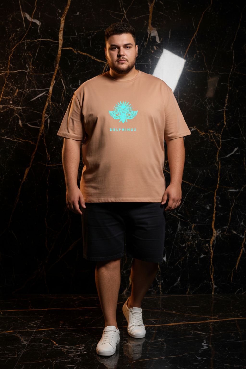 L'ÉVASION CURVE – T-shirt unisexe nude beige logo turquoise DELPHINUS, jeune homme curve décontracté, ambiance premium marbre noir et or, short et sneakers blanches, DELPHINUS