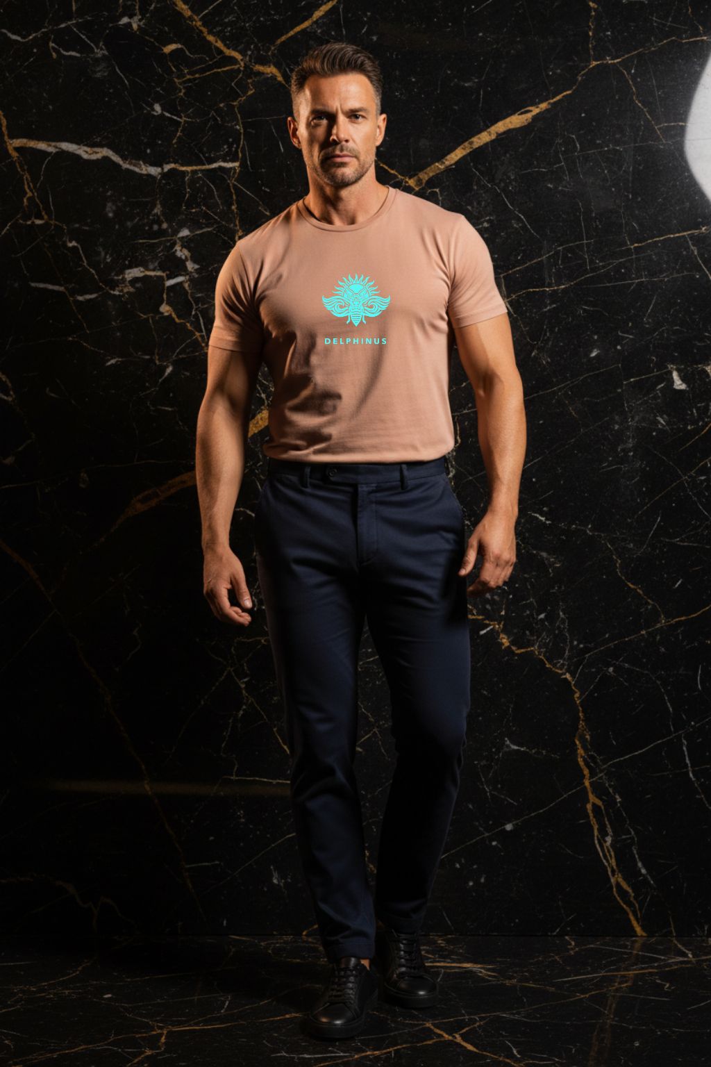 L'ÉVASION – T-shirt unisexe nude beige logo turquoise DELPHINUS, homme élégant et décontracté, ambiance premium marbre noir et or, pantalon chino sombre, DELPHINUS