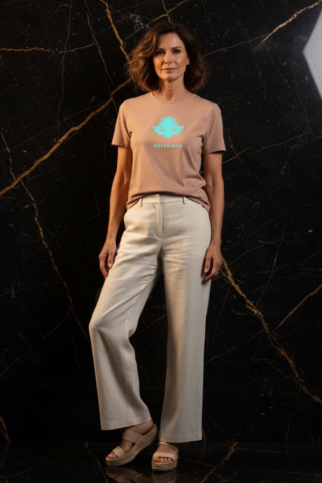 L'ÉVASION – T-shirt unisexe nude beige logo turquoise DELPHINUS, femme mature et raffinée, ambiance premium marbre noir et or, pantalon large et espadrilles, DELPHINUS