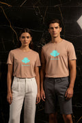 L'ÉVASION – T-shirt unisexe nude beige logo turquoise DELPHINUS, couple jeune et élégant, ambiance premium marbre noir et or, tenues estivales modernes, DELPHINUS