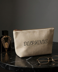 Trousse côtelée beige Le Nocturne DELPHINUS sur table marbre noir avec parfum Art Déco et lunettes dorées, ambiance masculine élégante, accessoire lifestyle luxe