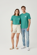 LA LAGUNE – T-shirt unisexe vert Peacock Green logo cigale blanc, jeune couple complice, marina Côte d'Azur lumière dorée, DELPHINUS