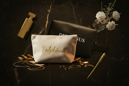 Duo Zénith DELPHINUS — L'Aurore trousse côtelée crème brodée or et L'Intrépide pochette oxford noire, posées ensemble sur marbre noir