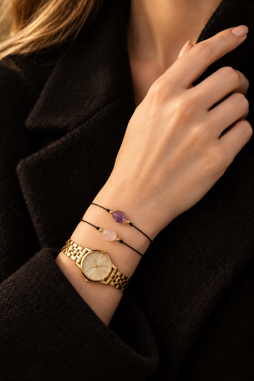 L'ÉTOILE – bracelets améthyste et quartz rose portés au poignet avec une montre dorée et un manteau noir, DELPHINUS