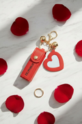 LE CŒUR VAGABOND – Bijou de sac porte-clé rouge, cœur miroir et grelots dorés sur marbre blanc, pétales de rose, DELPHINUS