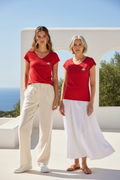 LE CARACTÈRE – Duo femme 20 ans et femme 50 ans en t-shirts rouges col V logo cigale blanc, terrasse villa vue mer, DELPHINUS