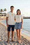 LE REFLET – t-shirt unisexe ivoire "La Vie Côté Soleil" jaune, couple homme short marine et femme jupe jean bord de mer, DELPHINUS
