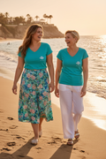 LE LAGON CURVE – T-shirt col V femme turquoise logo blanc, duo de femmes curve complices sur la plage, ambiance estivale, DELPHINUS
