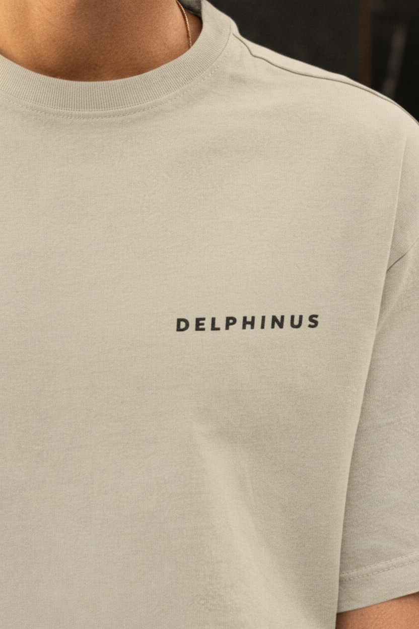 LE SIGNATURE CURVE – Gros plan inscription DELPHINUS imprimée poitrine gauche, t-shirt unisexe oversize sable de Camargue, qualité impression premium, DELPHINUS
